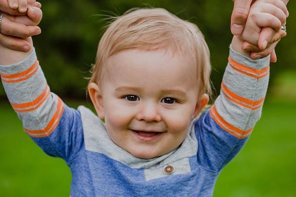 smiling infant holding hands with parents l infant dental care happy valley mn