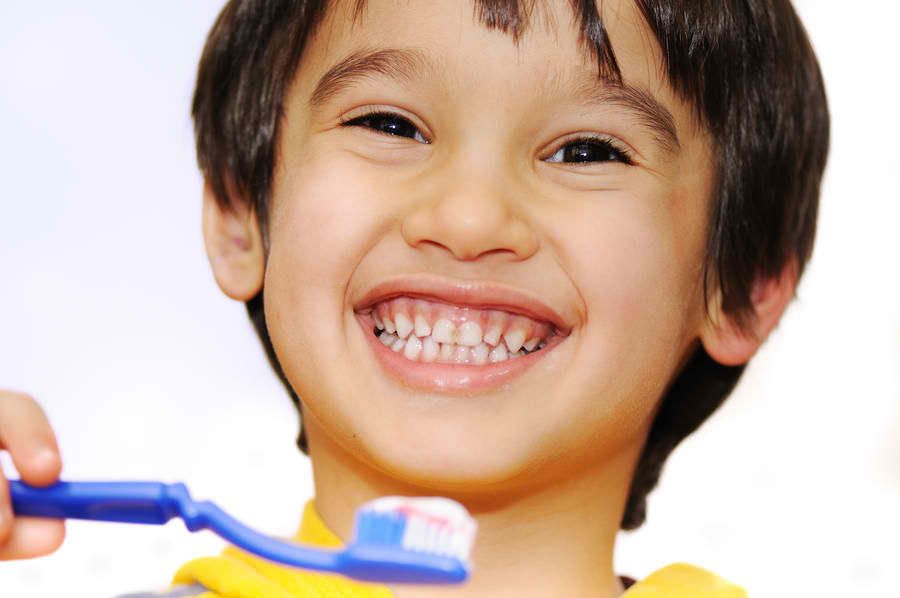 small boy in striped shirt brushing teeth | pediatric dentist near me