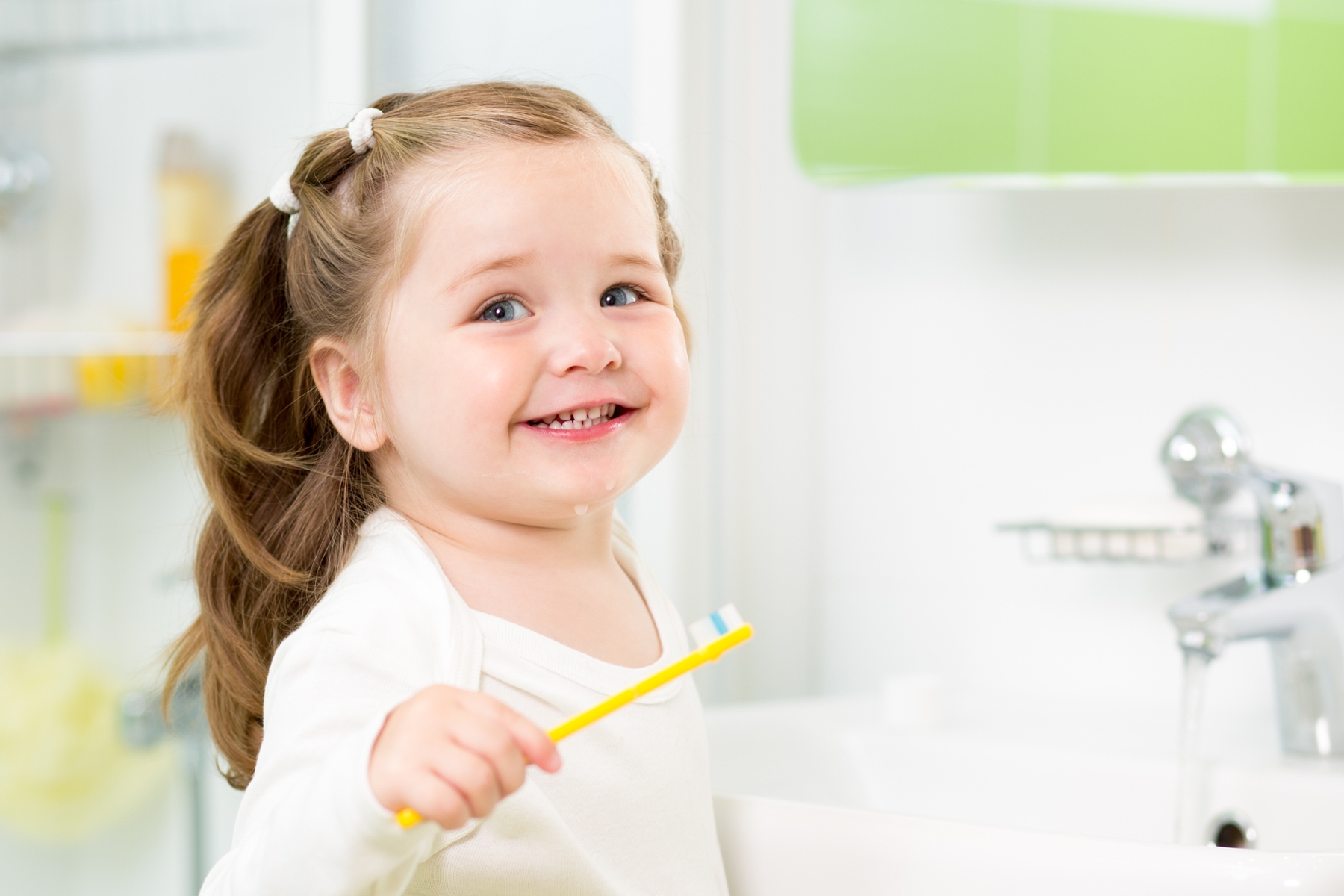baby girl with toothbrush in bathroom