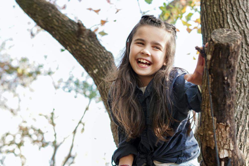 young girl playing in tree | preventive dental care apple valley