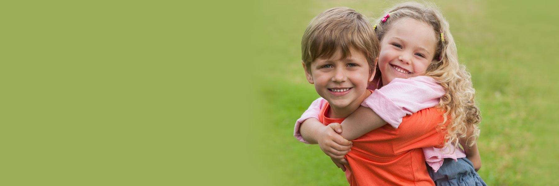 two children playing outside in grass | pediatric dentist near me