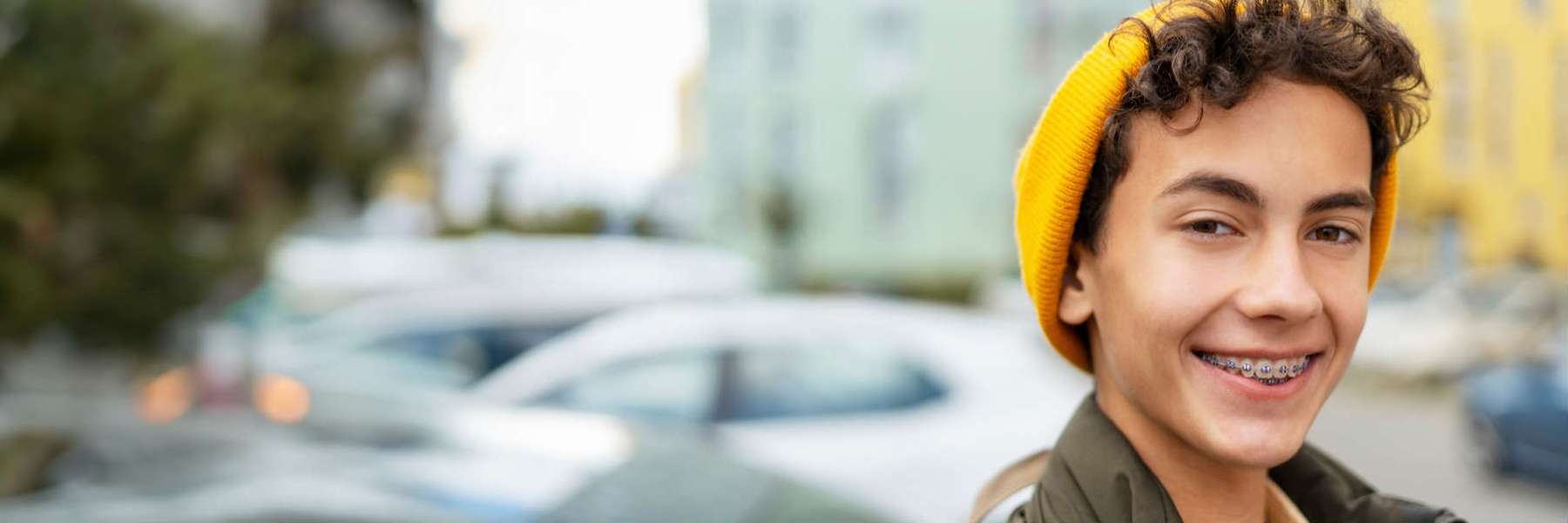 teen boy with yellow hat and braces smiling | board certified pediatric dentist