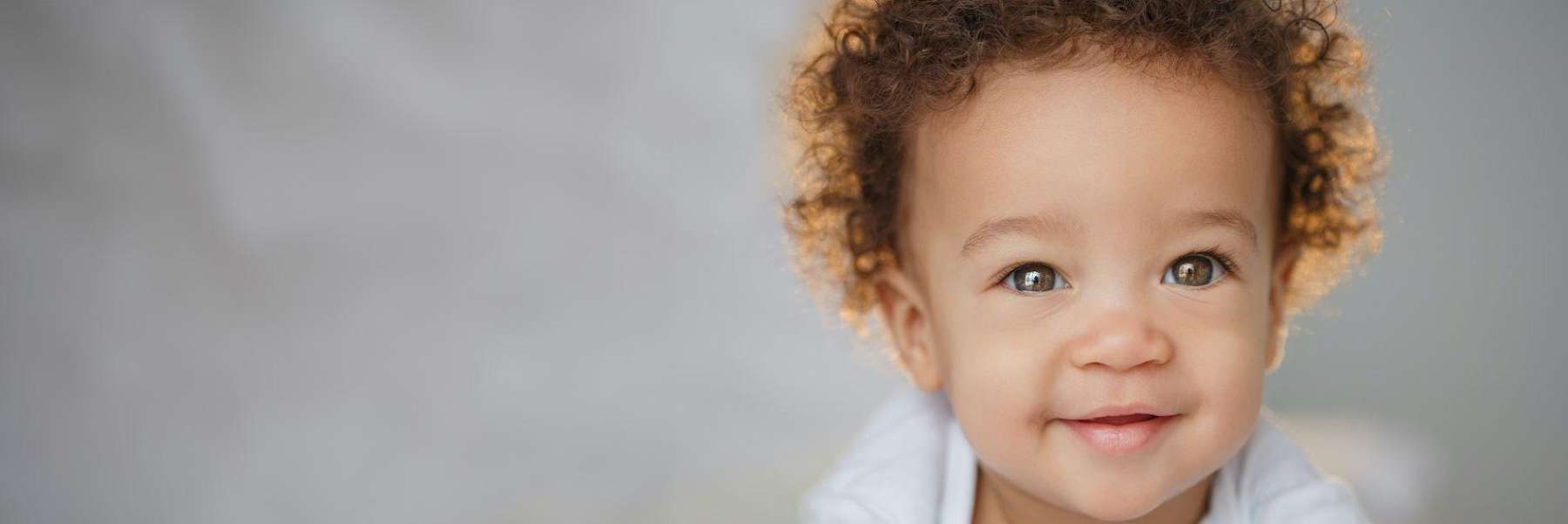 baby with curly hair smiling | child's dental exam
