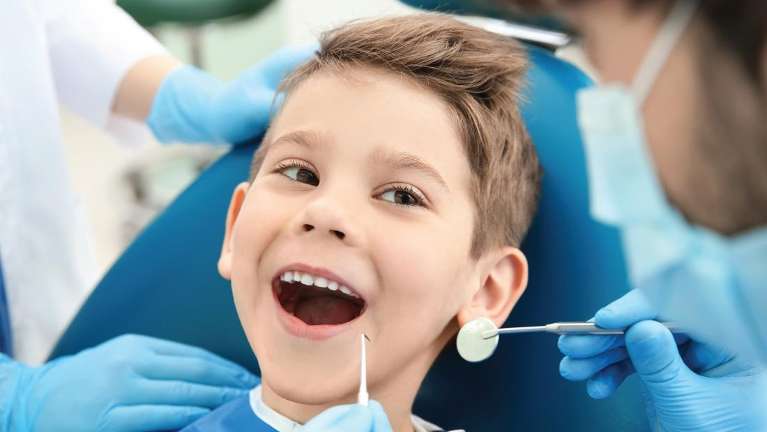 child sitting in dentist exam chair | child dental exam