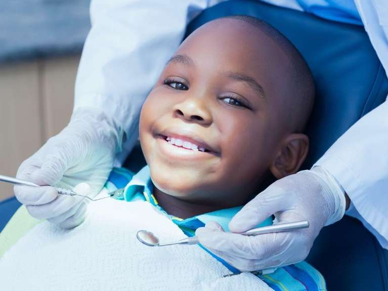 child sitting in dentist exam chair | child dental exam