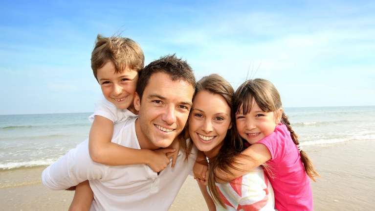 family of four hugging on beach | apple valley mn pediatric dentist
