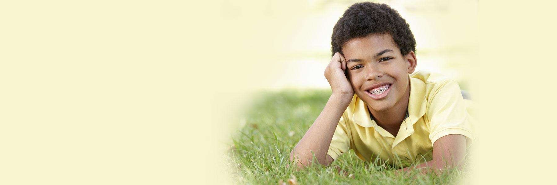 young boy laying in grass smiling | interceptive orthodontics apple valley