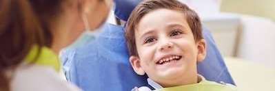 young boy smiling in dentist exam chair | urgent pediatric dental care