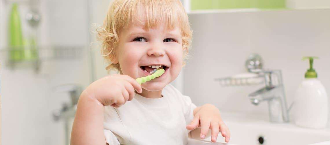 A happy child brushing teeth in a cheerful bathroom, showcasing early oral care.